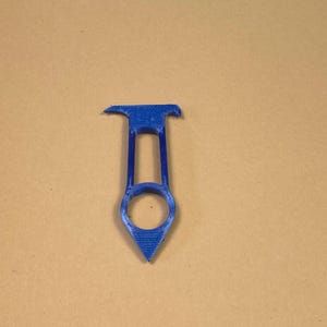 May include: A blue 3D-printed tool with a unique shape. It features a handle with a circular opening and a pointed end. The top has a flat, rectangular shape with two small protrusions. The tool is designed for a specific purpose.