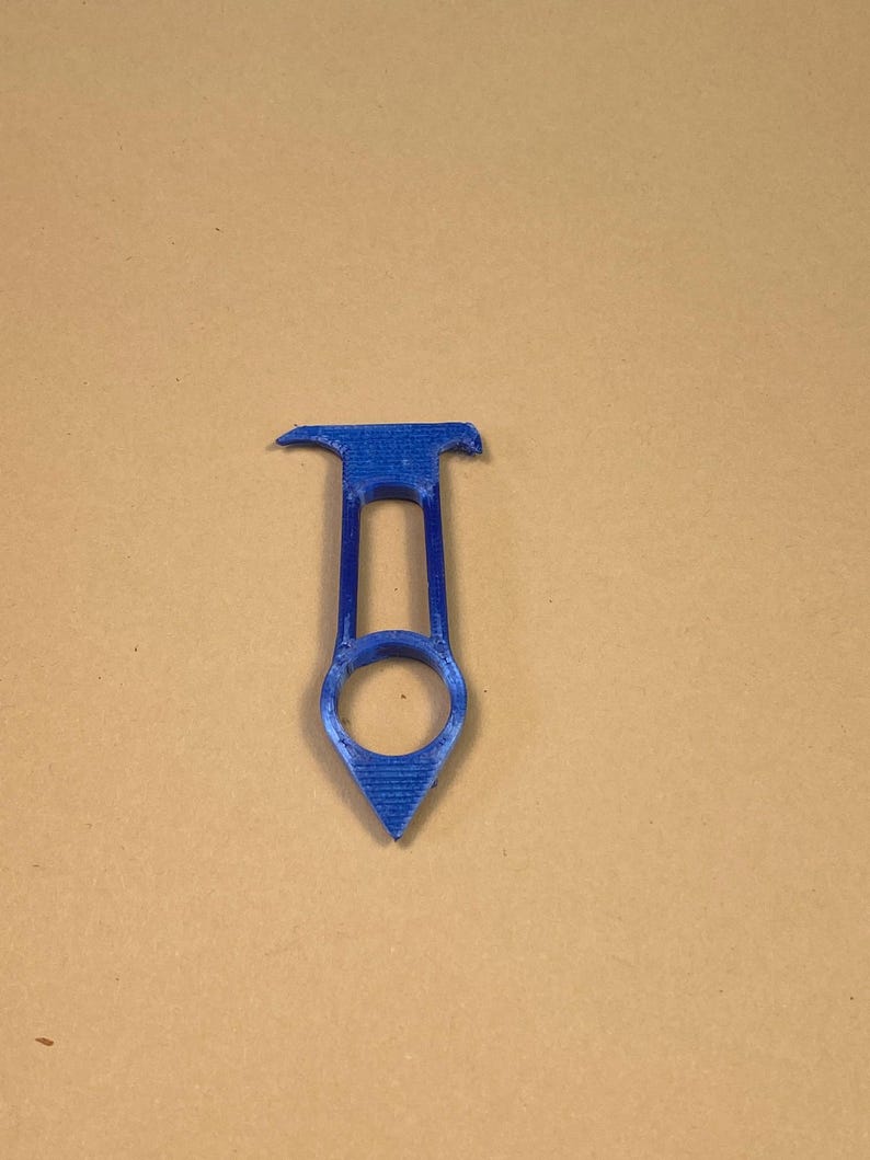 May include: A blue 3D-printed tool with a unique shape. It features a handle with a circular opening and a pointed end. The top has a flat, rectangular shape with two small protrusions. The tool is designed for a specific purpose.