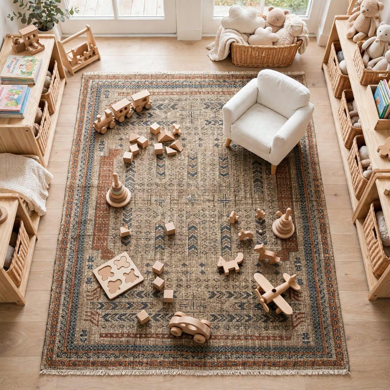 Puede incluir: Una alfombra rectangular con un patr&oacute;n geom&eacute;trico en marr&oacute;n, azul y crema con flecos, que presenta una colecci&oacute;n de juguetes de madera que incluye un tren, anillos apilables, bloques, un rompecabezas, un coche y un avi&oacute;n.
