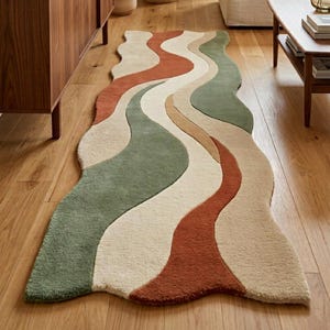 Puede incluir: Una alfombra pasillera larga y rectangular con un patrón orgánico ondulado de franjas fluidas en tonos verde salvia, naranja terracota, crema y beige. La alfombra tiene un pelo suave y texturizado con un diseño de borde curvo.