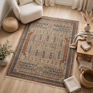 Puede incluir: Una alfombra rectangular con base beige y un patr&oacute;n geom&eacute;trico en tonos naranja &oacute;xido y azul marino. El dise&ntilde;o incluye motivos de flechas repetitivos y bordes lineales, rematado con flecos blancos cortos en los dos lados m&aacute;s cortos.