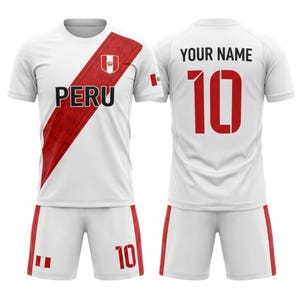 Peut inclure: Ensemble de maillot et short de football blancs avec des détails rouges. Le maillot affiche le mot "PERU" et le numéro "10" en rouge. Le drapeau péruvien est visible.