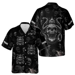 Puede incluir: Camisa negra con botones con un patrón de calaveras repetido y un gran gráfico de calavera en la espalda. El gráfico incluye una corona y cuernos. La camisa tiene las palabras "NAME" y "YOUR" impresas.