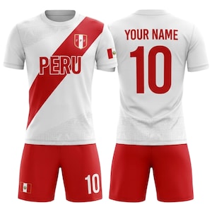 Peut inclure: Ensemble maillot et short de football du Pérou, blanc et rouge. Le maillot affiche le mot "PERU" et le numéro "10" au dos. Le short porte également le numéro "10". Le drapeau péruvien est présent sur le maillot et le short.