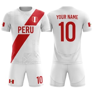 Peut inclure: Uniformes de football blancs avec des détails rouges, affichant le mot "PERU" et le numéro "10". Le maillot a une bande diagonale rouge et le drapeau péruvien sur la manche et le short. Le texte "YOUR NAME" est au-dessus du numéro 10 au dos.