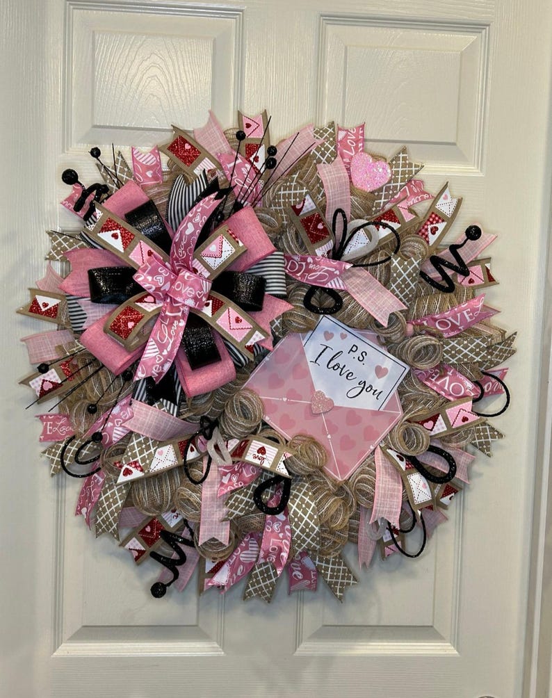 May include: A pink and brown Valentine's Day wreath with a burlap base, pink and white ribbon, and a pink envelope with the text "P.S. I love you".