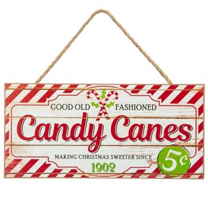 May include: A red and white striped wooden sign with the text "Good Old Fashioned Candy Canes Making Christmas Sweeter Since 1902 5¢" and a graphic of two crossed candy canes.
