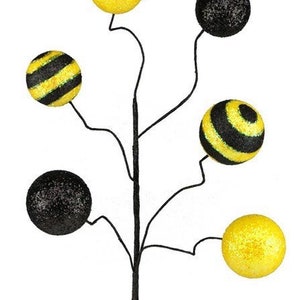 May include: A black wire stem with five round ornaments. The ornaments are yellow, black, and yellow and black striped.
