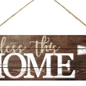 May include: A wooden sign with a rustic brown finish and white lettering that reads "Bless this HOME". A white cross with a brown floral design is on the right side of the sign. The sign is hanging from a twine rope.