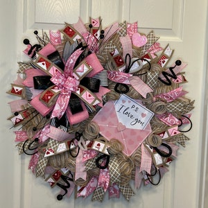 May include: A pink and brown Valentine's Day wreath with a burlap bow and a pink envelope with the text "P.S. I love you".
