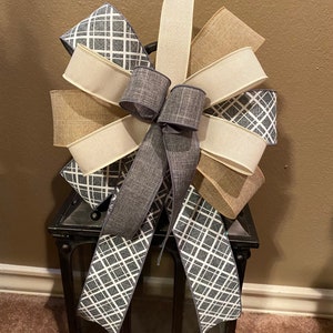 May include: A gray, white, and beige bow with a plaid pattern is tied around a black metal lantern.
