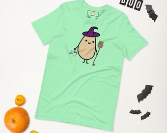 May include: A light green t-shirt featuring a cartoon potato character dressed as a witch, holding a broom. The potato wears a purple witch hat and has the word "wiley" printed on the shirt. Halloween-themed decorations are in the background.