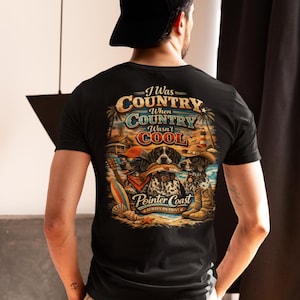 Puede incluir: Camiseta negra con un gráfico de tres perros con sombreros de vaquero y pañuelos, el texto "I Was Country When Country Wasn't Cool" y "Pointer Coast Always on Point".