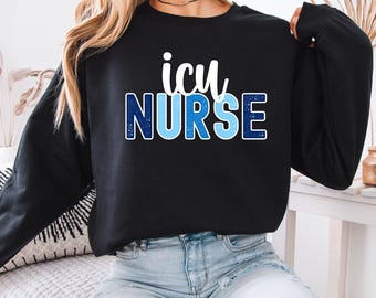 May include: Black sweatshirt with the text "icu NURSE" in white and blue lettering. The word "icu" is in a script font, and "NURSE" is in a bold, block font. The sweatshirt is worn by a person.