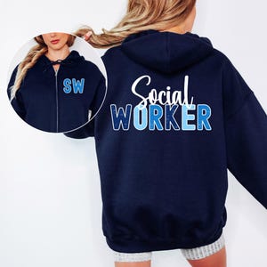 May include: Navy blue zip-up hoodie with the text "Social Worker" in white and blue. The letters "SW" are on the chest. The hoodie has a drawstring hood and a full-length zipper. The design is a great gift for social workers.