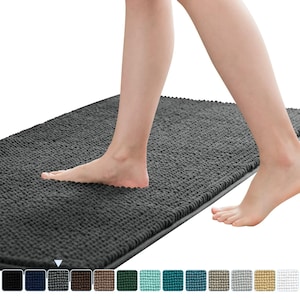 May include: A dark gray rectangular bath mat with a textured, plush surface. The mat is shown with a person's feet stepping onto it. Several color options are displayed at the bottom of the image.