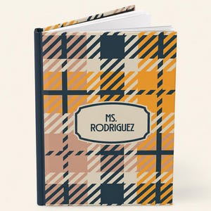 May include: A hardcover journal featuring a plaid pattern in shades of mustard yellow, navy blue, and cream. A central cream-colored label with a dark blue border displays the text "MS. RODRIGUEZ" in a dark blue, sans-serif, uppercase font.