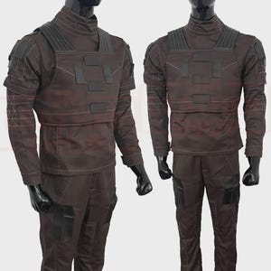 May include: Two brown tactical outfits displayed on mannequins. Each outfit includes a long-sleeved shirt with a high collar, a chest rig with black accents, and matching pants with pockets. The outfits are designed with a utilitarian aesthetic.