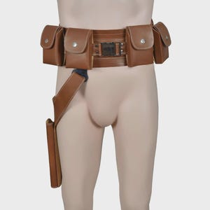 May include: A brown leather utility belt with multiple pouches and a holster. The belt has a rectangular buckle and is designed to be worn around the waist. The pouches have a flap closure with a silver button.