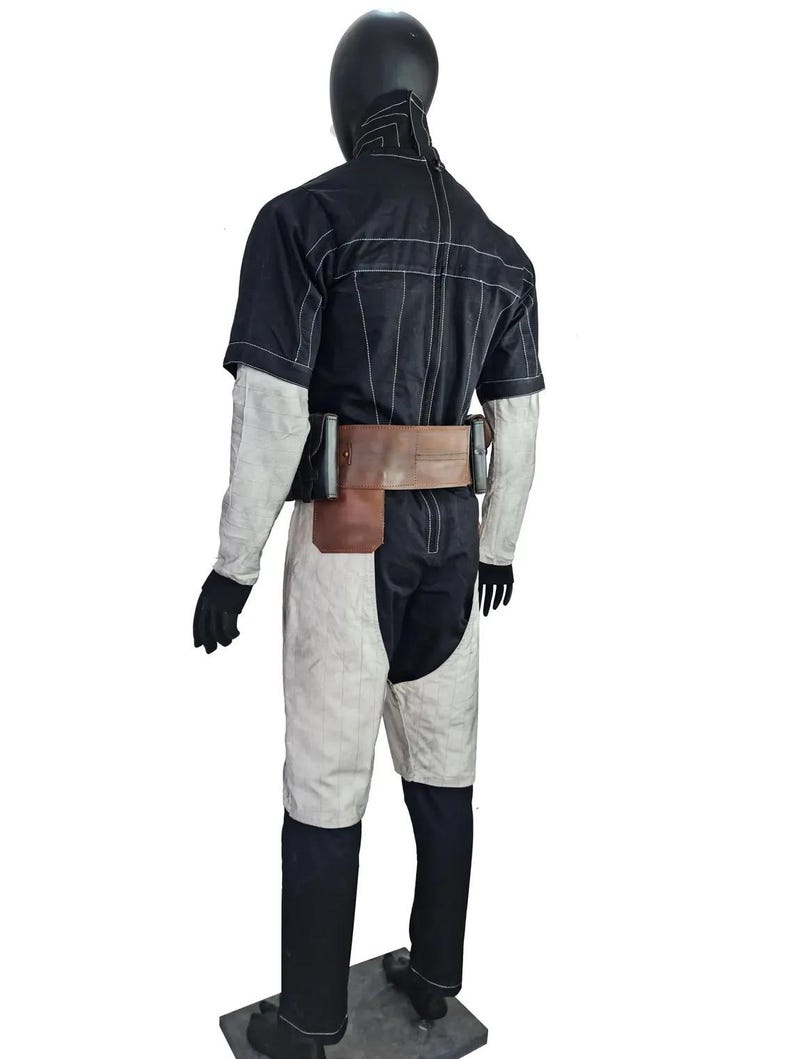 May include: A black and white costume displayed on a mannequin. The outfit includes a short-sleeved black top with white stitching, white and black trousers, a brown belt with pouches, and black gloves. The mannequin has a black head covering.