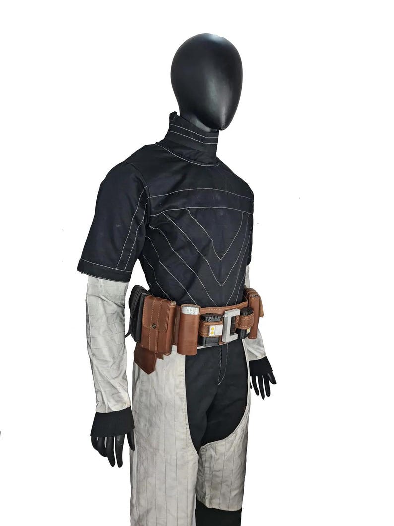 May include: A black and white jumpsuit with a high collar and short sleeves. The outfit features white stitching and a brown utility belt with pouches and a silver buckle. Black gloves complete the look.