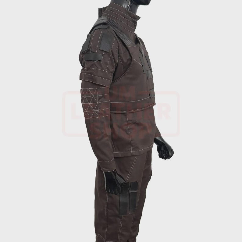 May include: Brown tactical uniform with black accents, displayed on a mannequin. The outfit features a high collar, shoulder pads, and multiple pockets. White stitching details the design. The mannequin's hands are covered with black gloves.