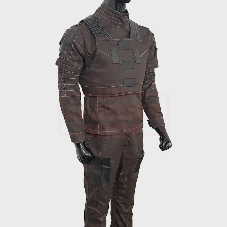 May include: A brown tactical uniform, consisting of a long-sleeved shirt, vest, and pants. The uniform features black accents, reinforced stitching, and multiple pockets. The mannequin is wearing a high-collared shirt.