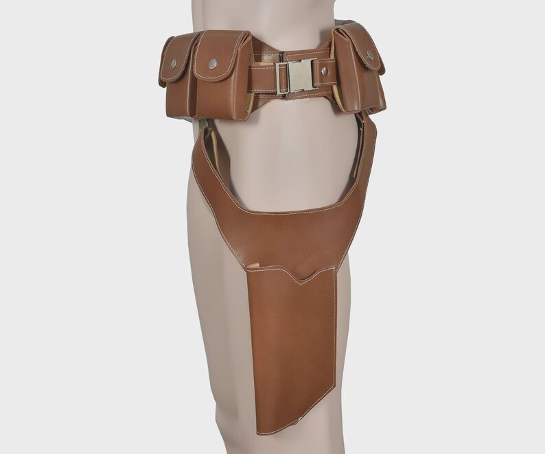 K&ouml;nnte beinhalten: Brauner Leder-Utility-G&uuml;rtel mit mehreren Taschen und einem Holster. Der G&uuml;rtel hat eine silberfarbene Schnalle und ist f&uuml;r das Tragen um Taille und Oberschenkel konzipiert. Die Taschen haben Knopfverschl&uuml;sse und wei&szlig;e N&auml;hte.