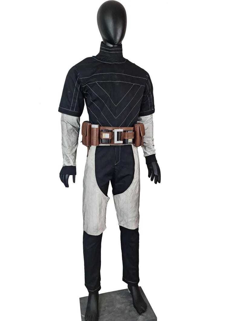 May include: A black and white costume on a mannequin. The outfit features a black top with white stitching, a brown belt with pouches, and black trousers with white accents. The mannequin stands on a grey base.