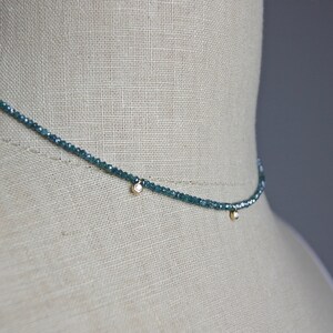 May include: A delicate necklace made of small, blue gemstone beads with two small, round, clear diamond accents.