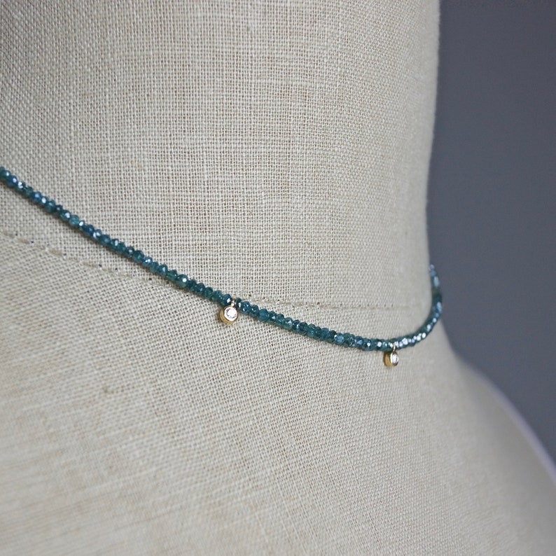 May include: A delicate necklace made of small, blue gemstone beads with two small, round, clear diamond accents.