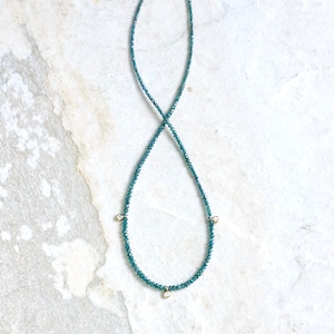 May include: A delicate necklace made of blue gemstones with three small diamond accents.