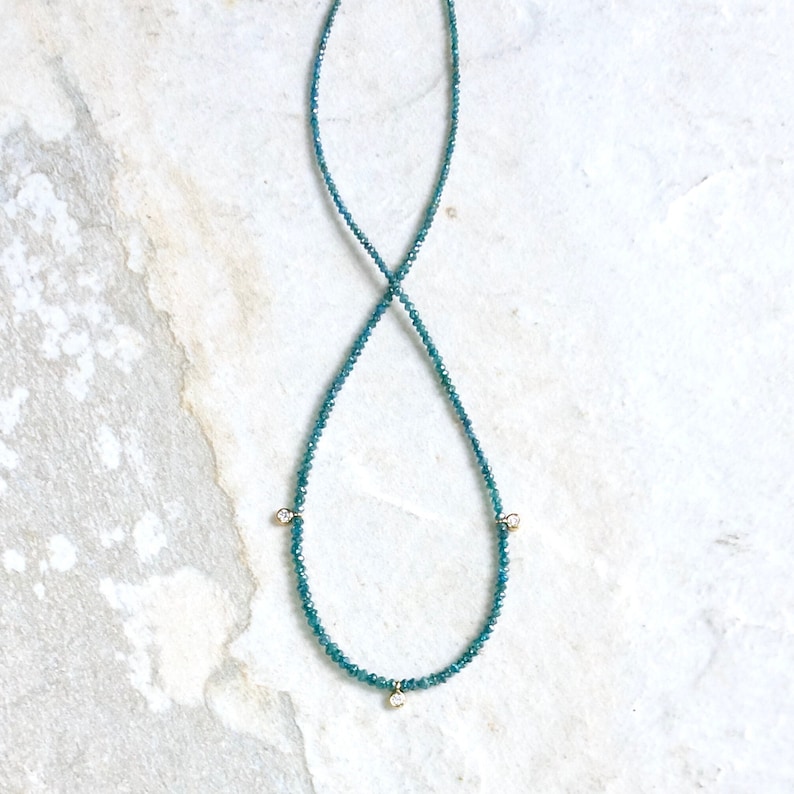 May include: A delicate necklace made of blue gemstones with three small diamond accents.