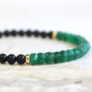 May include: A black and green beaded bracelet with gold accents. The bracelet is made with black onyx and green jade beads.