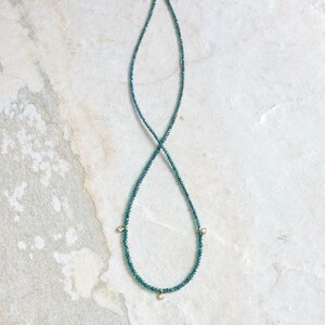 May include: A delicate necklace made of blue gemstones with three small diamond accents.