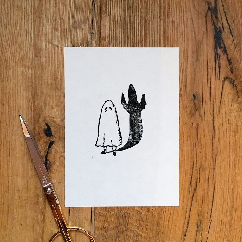 Puede incluir: Una ilustraci&oacute;n en blanco y negro de un fantasma con una cara triste y una sombra detr&aacute;s. El fantasma lleva una simple t&uacute;nica blanca y tiene brazos y piernas peque&ntilde;os.