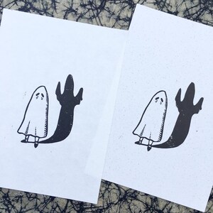 Puede incluir: Dos ilustraciones en blanco y negro de un fantasma con una sombra. El fantasma es blanco y la sombra es negra. El fantasma est&aacute; de pie con los brazos levantados y su sombra est&aacute; llegando hacia arriba.