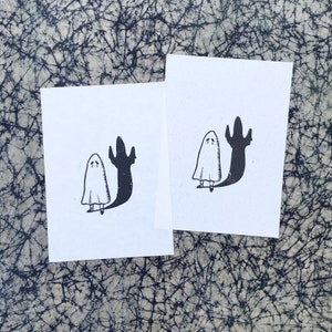 Puede incluir: Dos ilustraciones en blanco y negro de un fantasma con una sombra. El fantasma es blanco y la sombra es negra. El fantasma est&aacute; de pie con los brazos levantados y la cabeza inclinada hacia abajo. La sombra est&aacute; de pie con los brazos levantados y la cabeza inclinada hacia abajo.