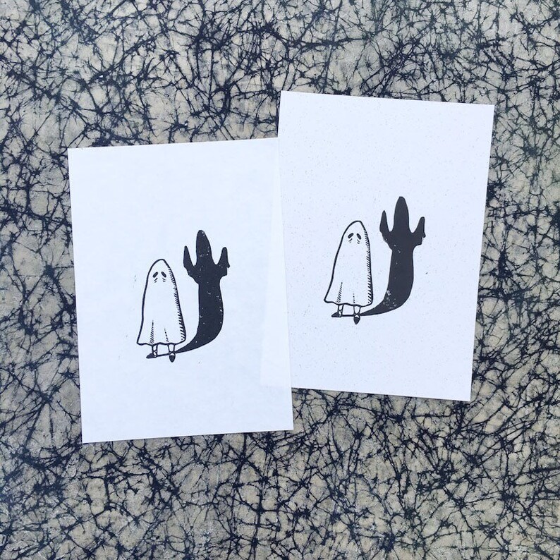 Puede incluir: Dos ilustraciones en blanco y negro de un fantasma con una sombra. El fantasma es blanco y la sombra es negra. El fantasma est&aacute; de pie con los brazos levantados y la cabeza inclinada hacia abajo. La sombra est&aacute; de pie con los brazos levantados y la cabeza inclinada hacia abajo.