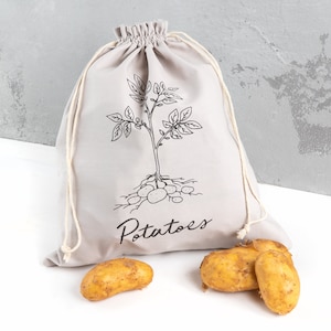 May include: A grey cotton drawstring bag with a black line drawing of a potato plant and the word "Potatoes". Four yellow potatoes are in front of the bag.