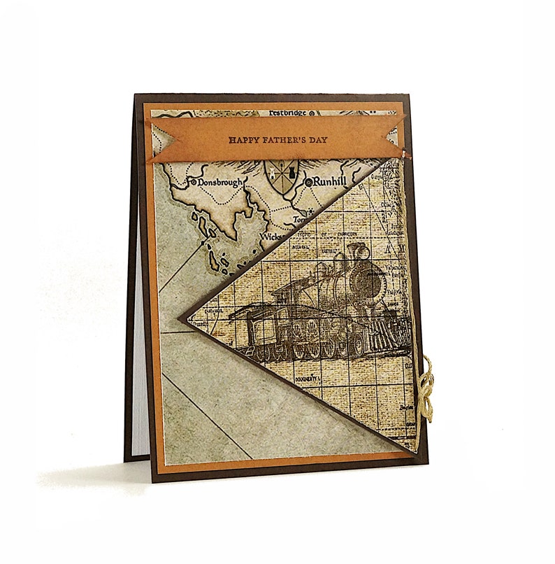 May include: A handmade Father's Day card with a vintage map and train design. The card features a brown and tan color scheme, with the words "Happy Father's Day" on a banner. A small gold twine is tied on the side.