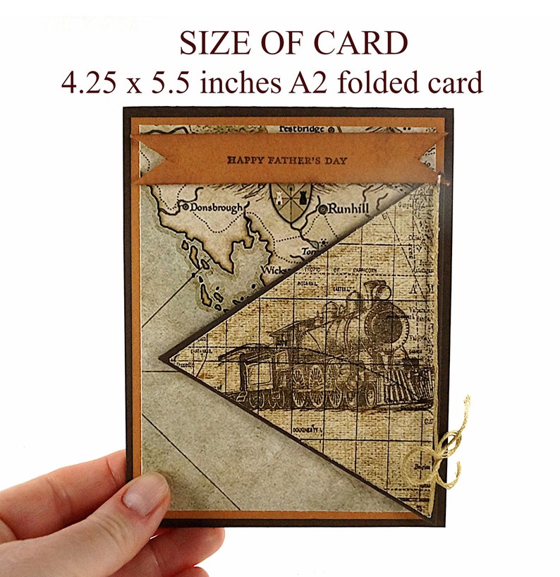 May include: A Father's Day card with a vintage map and train design. The card is 4.25 x 5.5 inches. It features a brown banner with "HAPPY FATHER'S DAY" and a sepia-toned map and train illustration. The card is held by a hand.