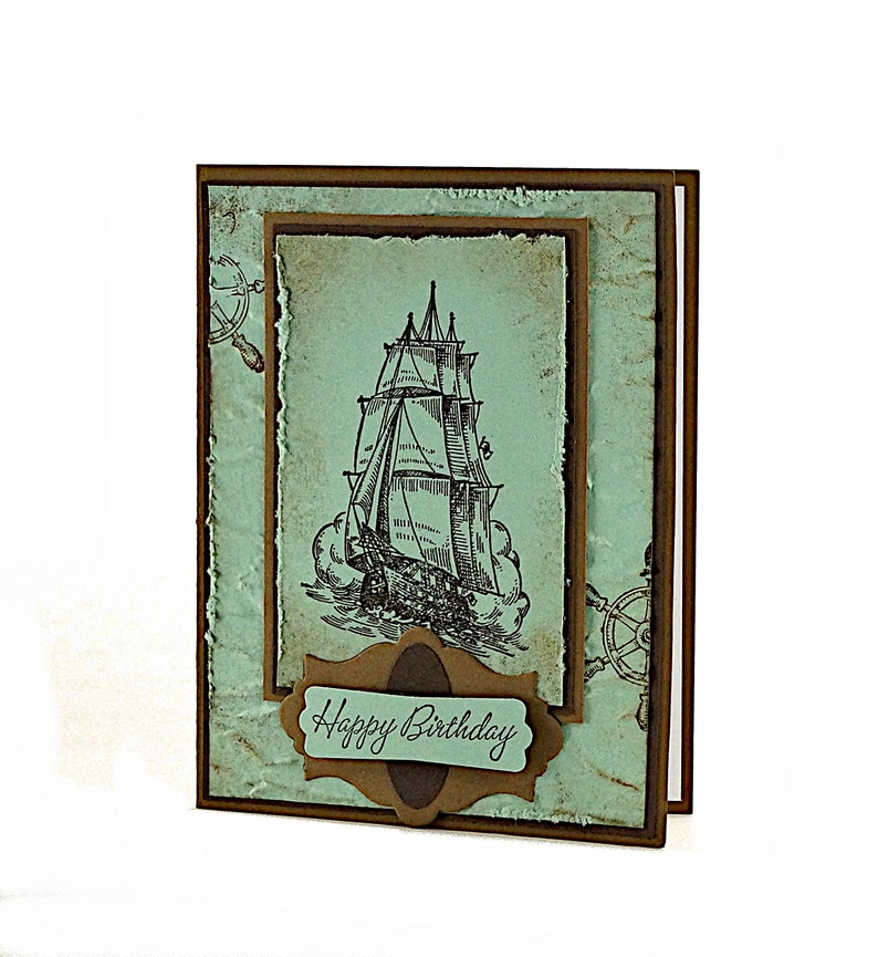 May include: A handmade birthday card with a vintage nautical theme. The card features a black and white illustration of a sailing ship with the words "Happy Birthday" on a brown banner.