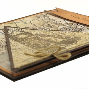May include: A handmade retirement card with a vintage map design. The card features a layered construction with a brown and tan color scheme. A banner with "Happy Retirement" is attached. The card is tied with twine.
