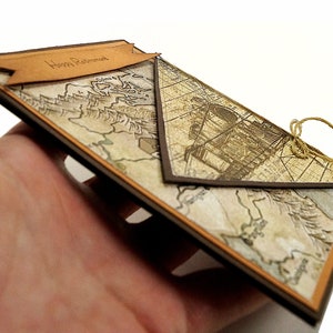 May include: A handmade retirement card with a vintage map design. The card features a brown border and a banner that reads "Happy Retirement." A twine bow secures the card's flap.