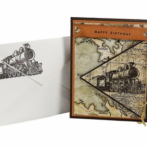 May include: A birthday card with a vintage train illustration and a matching envelope. The card features a map design with a banner that reads "HAPPY BIRTHDAY". The envelope has a train illustration.