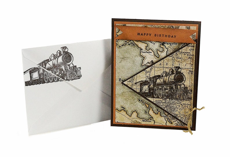 May include: A birthday card with a vintage train illustration and a matching envelope. The card features a map design with a banner that reads "HAPPY BIRTHDAY". The envelope has a train illustration.