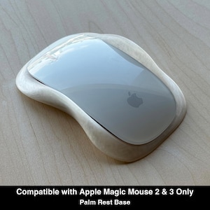 以下が含まれることがあります： Apple Magic Mouse用に設計された、白く真珠のような光沢のある人間工学に基づいたパームレストベース。デバイスを包み込む滑らかで輪郭のある形状が特徴です。下部には「Compatible with Apple Magic Mouse 2 & 3 Only」というテキストが印刷されています。