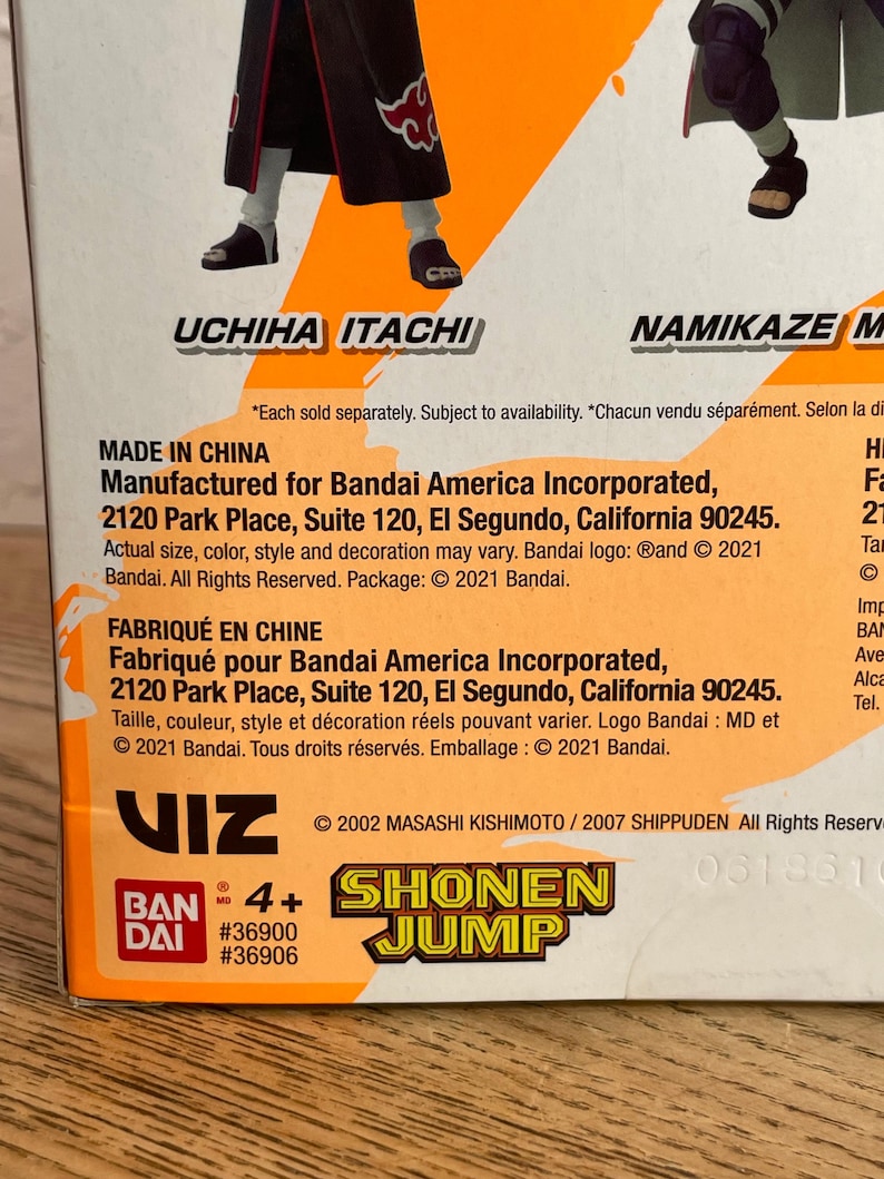 May include: A product box featuring the text "UCHIHA ITACHI" and "NAMIKAZE M". The box includes the "SHONEN JUMP" logo and the text "MADE IN CHINA". The box is orange and white.