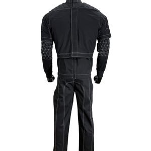 May include: Black jumpsuit with white stitching and geometric patterned accents on the sleeves. The outfit is displayed on a mannequin. The jumpsuit has a high collar and long sleeves. The pants are straight-legged.